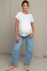 woman wearing a white maternity t-shirt and light blue wide-leg jeans, showing her baby bump