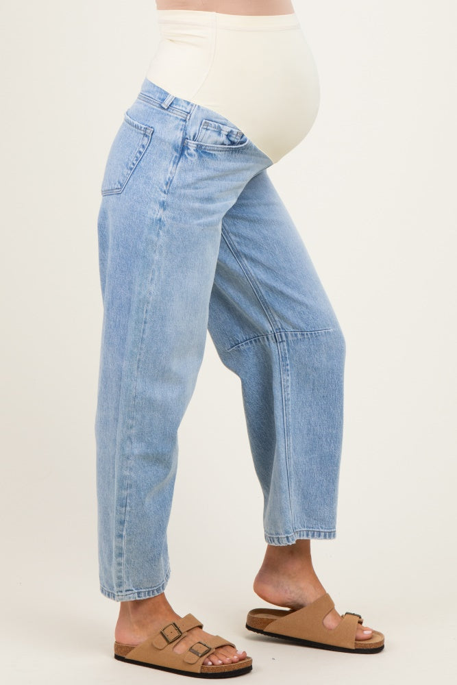 woman wearing light blue maternity jeans with a supportive belly band and casual brown sandals, baby bump visible