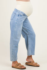 woman wearing light blue maternity jeans with a supportive belly band and casual brown sandals, baby bump visible
