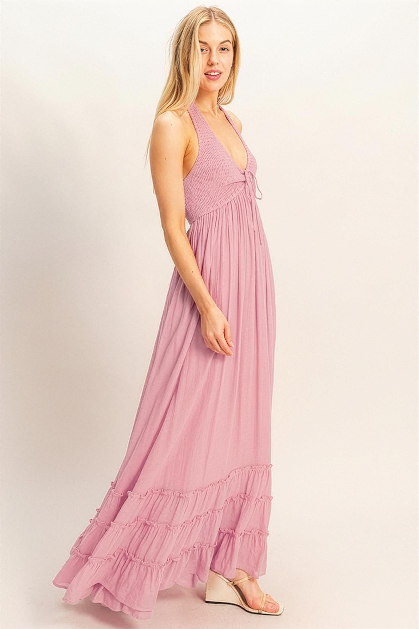woman wearing a light pink halter neck maxi dress with ruffled hem and a fitted bodice