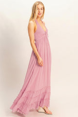 woman wearing a light pink halter neck maxi dress with ruffled hem and a fitted bodice