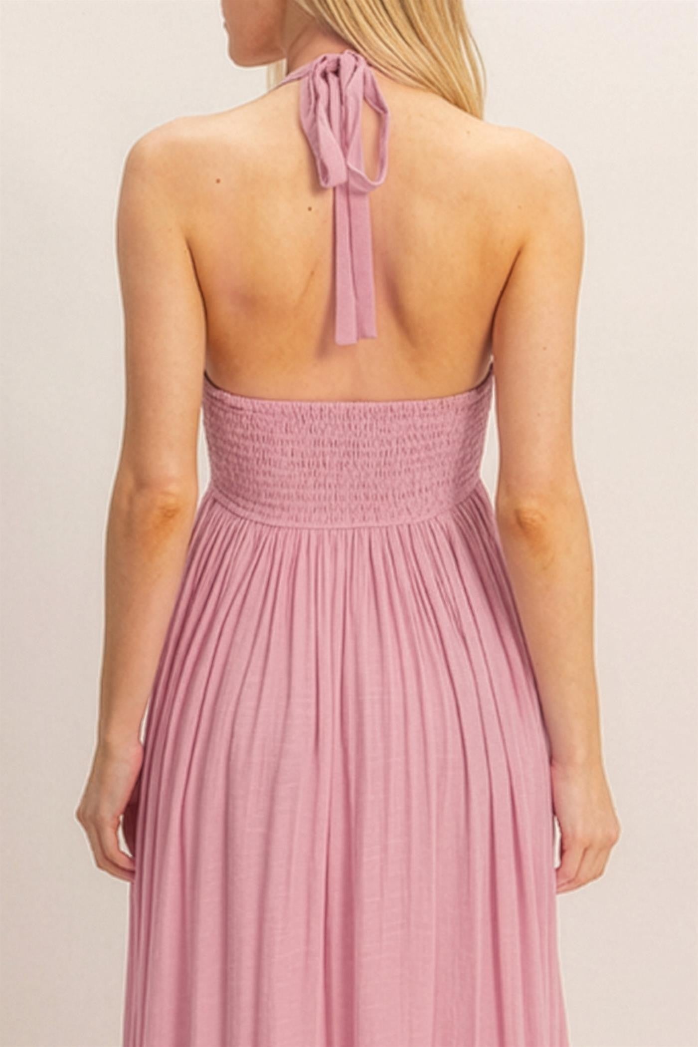woman wearing a back view of a light pink halter neck maxi dress with a smocked bodice