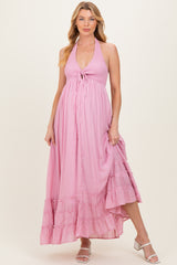 woman wearing a pink halter neck maternity dress with a tiered ruffle skirt and a baby bump visible
