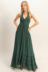 woman wearing a dark green halter neck maxi dress with a smocked bodice and tiered ruffle hem