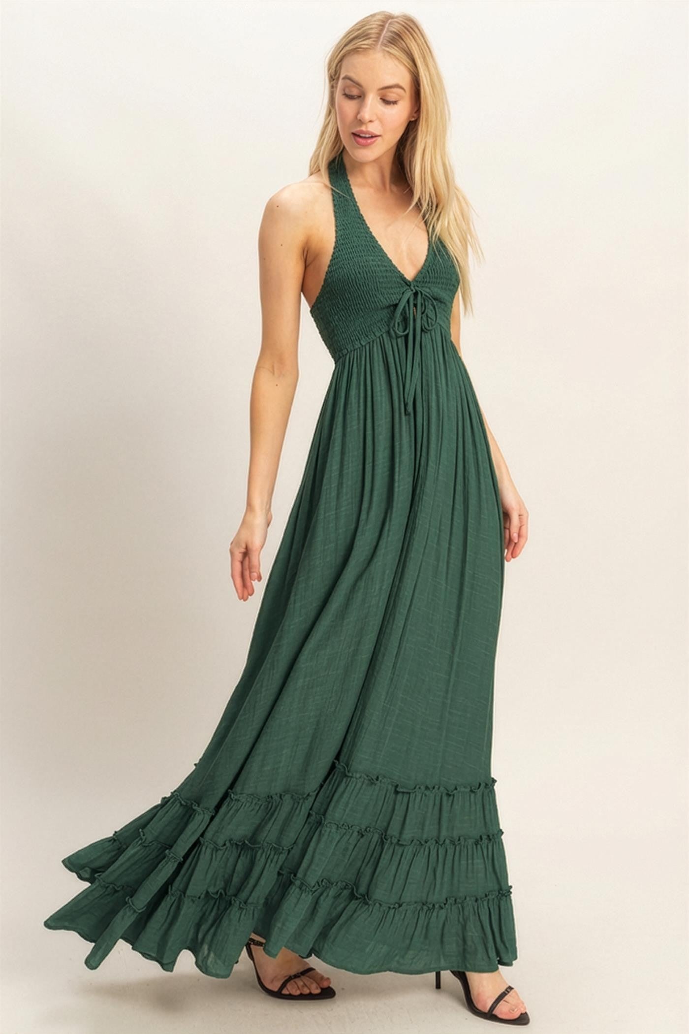 woman wearing a green halter neck maxi dress with a smocked bodice and ruffled hemline