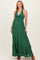 woman wearing a green halter maternity maxi dress with a tie detail and ruffle hem, showcasing her baby bump