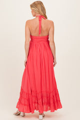 woman wearing a coral maternity maxi dress with a smocked back and ruffled hemline, showing a baby bump