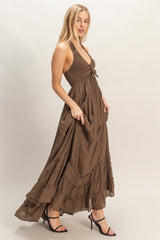 woman wearing a brown halter neck maxi dress with ruffles and a smocked bodice, standing sideways