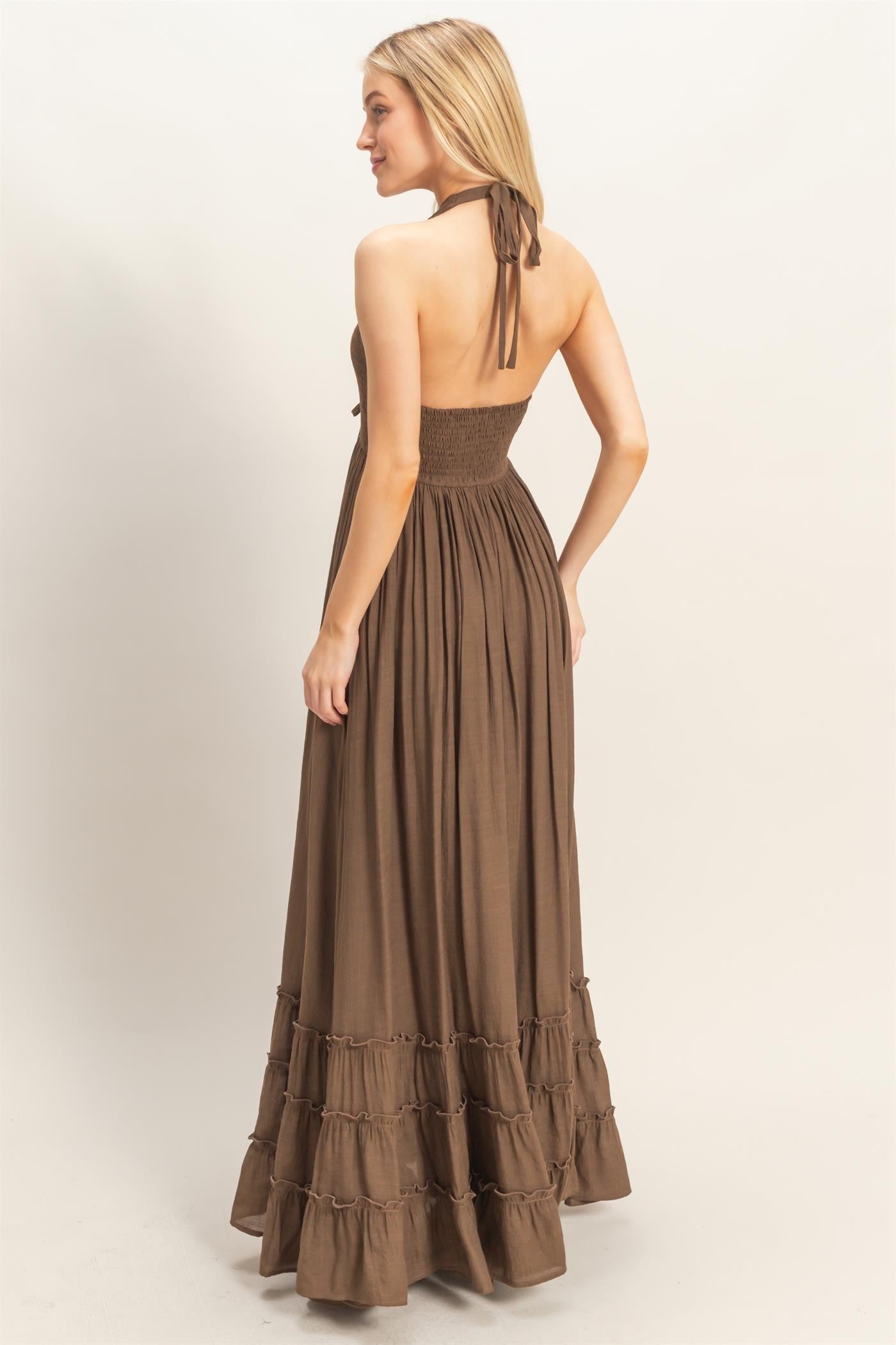 woman wearing a brown halter top maxi dress with a smocked bodice and tiered ruffle hemline, viewed from the back