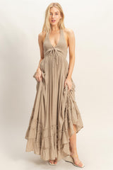 woman wearing a taupe halter neck maxi dress with a tied front and ruffle hem