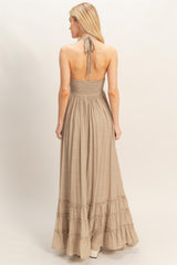 woman wearing a light brown halter-style maxi dress with a smocked bodice and tiered ruffle hem