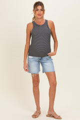woman wearing a black and white striped maternity tank top and denim shorts, standing and smiling.