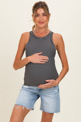 woman wearing a black and white striped maternity tank top and denim shorts, gently holding her baby bump