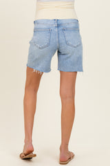 woman wearing light blue maternity denim shorts with frayed hem, standing with back to camera and wearing flat sandals