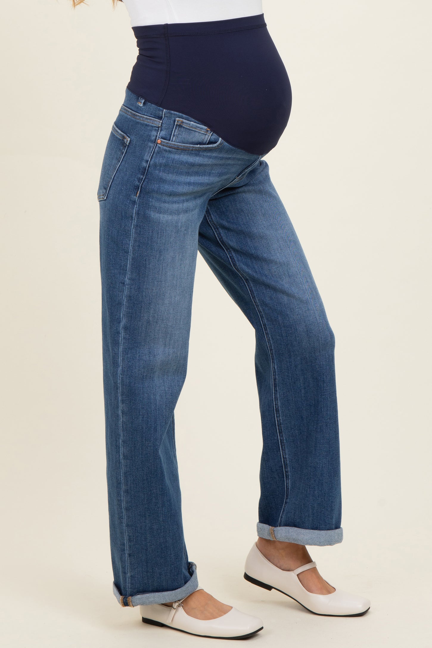 woman wearing a pair of blue maternity jeans with a dark blue over-the-bump waistband and a visible baby bump