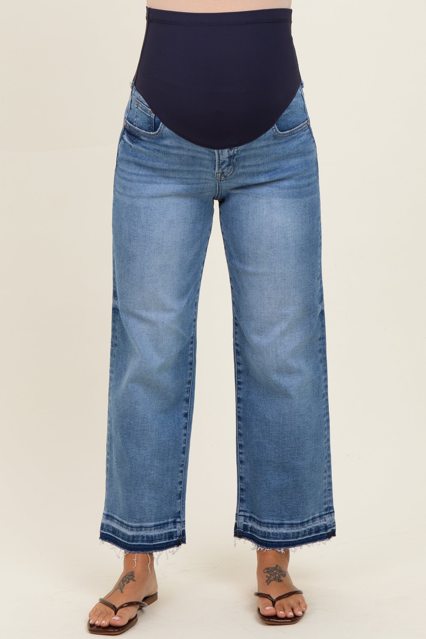 maternity wear light wash wide leg jeans with a dark blue over-the-bump waistband, model wearing flip-flops