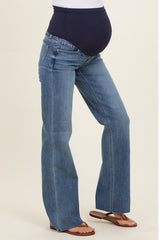 woman wearing blue maternity flared jeans with a stretchy black belly panel and showing her baby bump