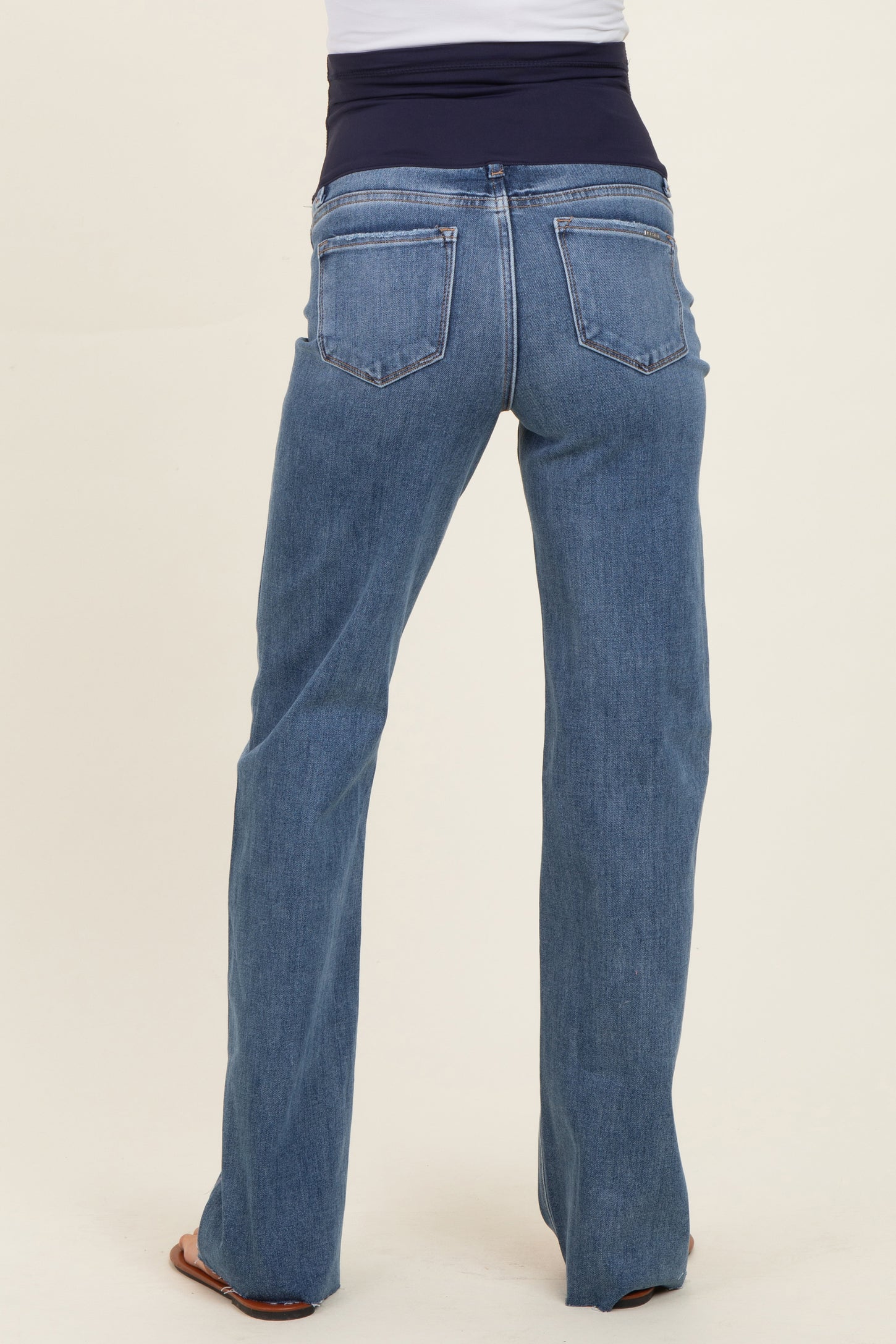 woman wearing light blue maternity jeans with a wide black waistband, viewed from the back