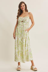 woman wearing a floral maxi dress with a ruched bodice and adjustable straps, standing with hands in pockets
