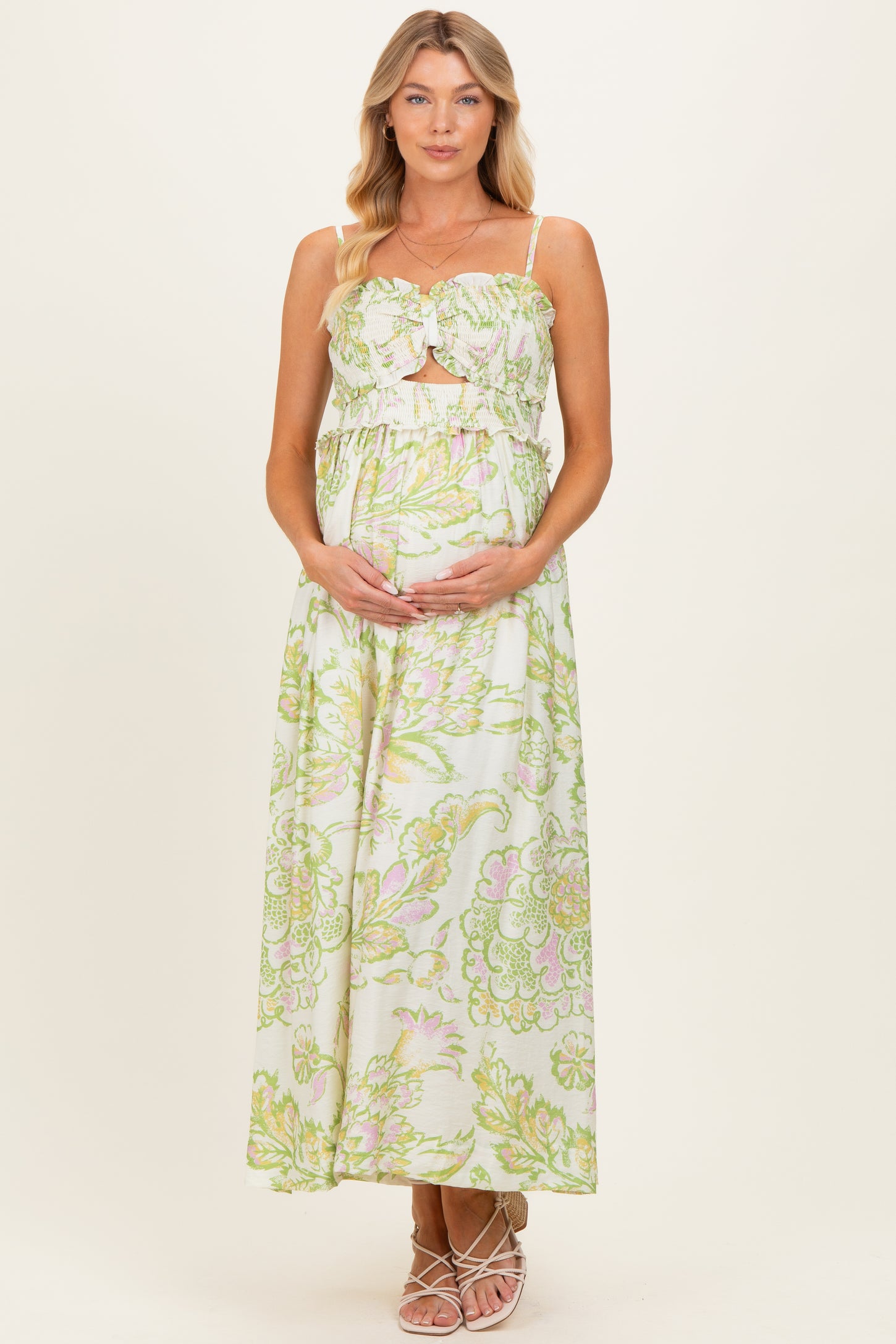 woman wearing a floral print maternity maxi dress with a cutout detail and holding her baby bump