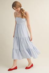 woman wearing a blue and white striped midi dress with a tiered skirt and red flats