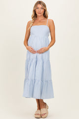 woman wearing a light blue striped maternity dress with a tiered skirt and holding her baby bump