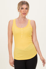 woman wearing a yellow ribbed tank top with a button detail, styled with black leggings