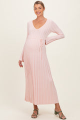woman wearing a light pink long sleeve ribbed maternity dress with a tie waist and a visible baby bump