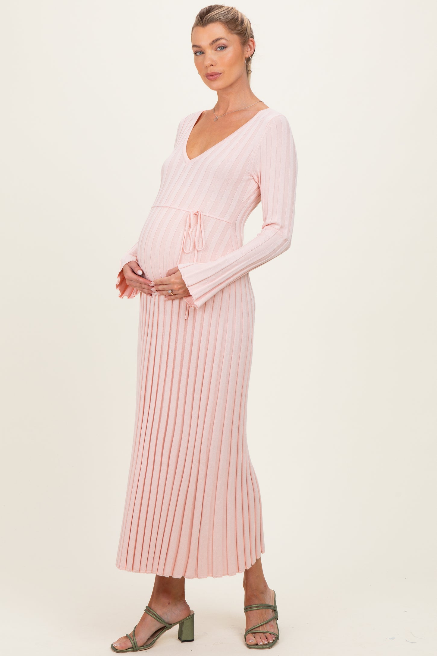woman wearing a light pink ribbed maternity dress with a tie waist and a visible baby bump