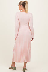 woman wearing a long pink ribbed maternity dress with long sleeves, viewed from the back