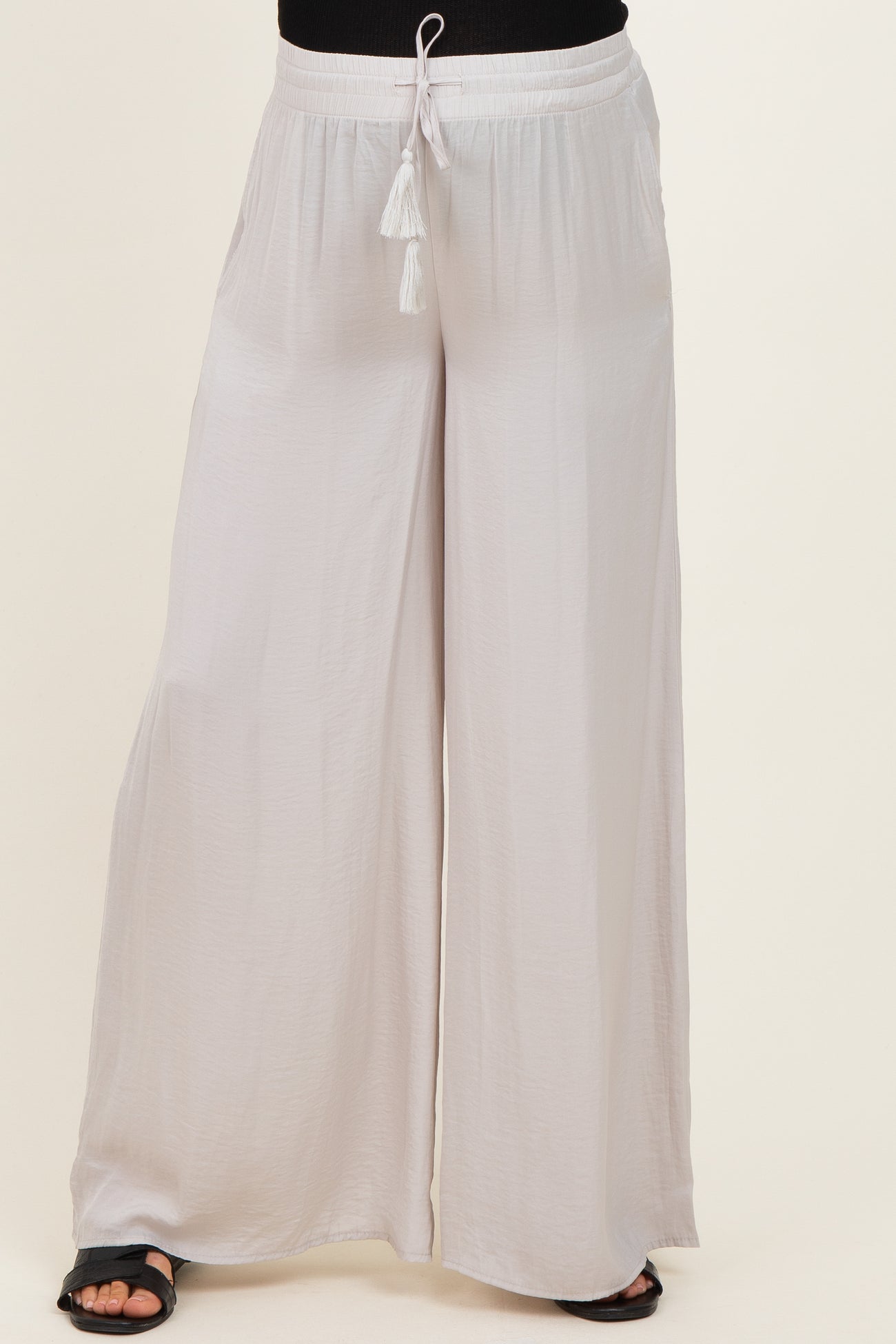 woman wearing light gray wide-leg maternity pants with a drawstring waist and tassel details