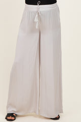 woman wearing light gray wide-leg maternity pants with a drawstring waist and tassel details