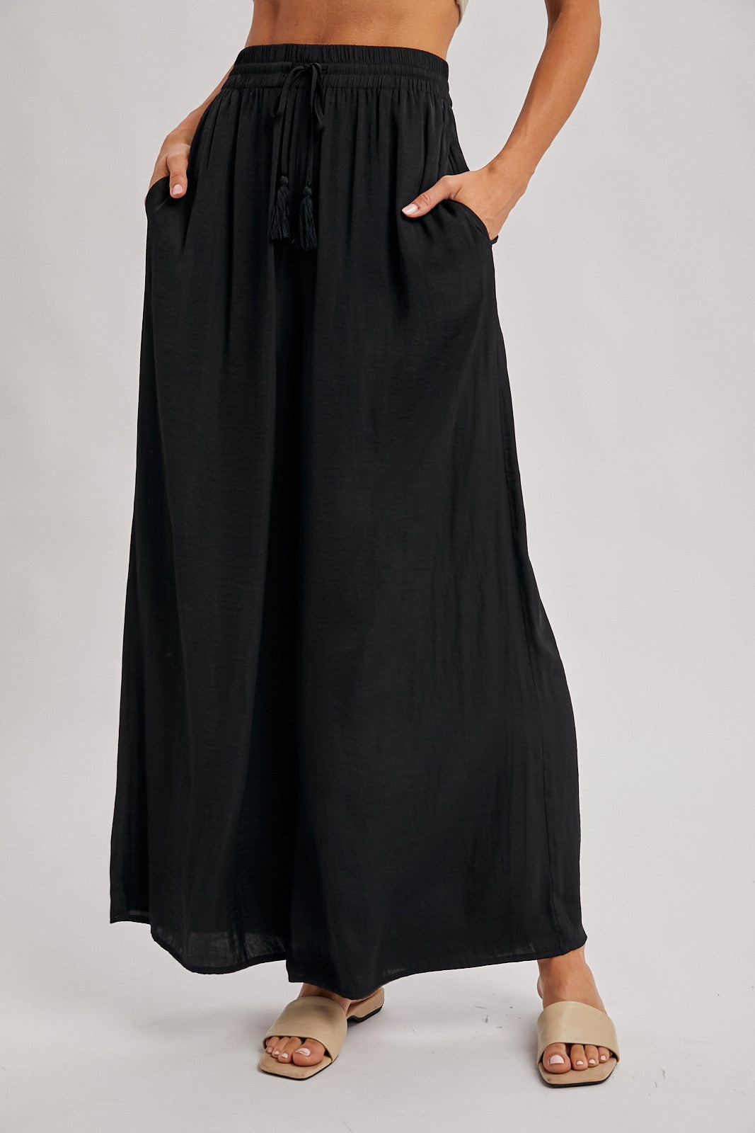 woman wearing a black maxi skirt with drawstring and pockets, styled with slide sandals