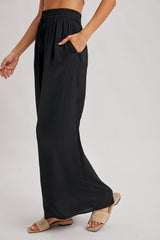 woman wearing black wide-leg pants with an elastic waistband and side pockets, styled with beige sandals