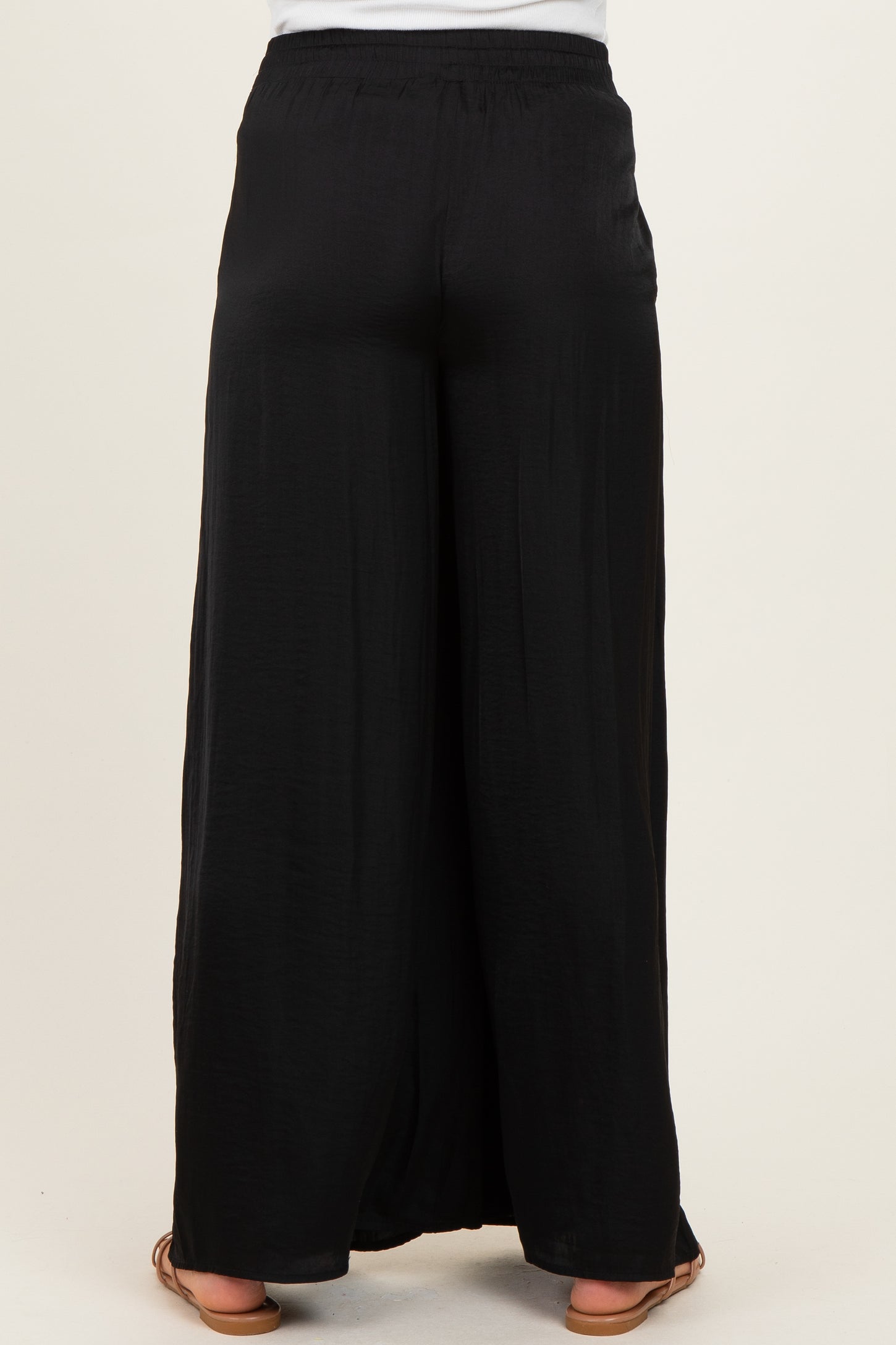 woman wearing black maternity wide-leg pants, seen from the back, features a comfortable elastic waistband