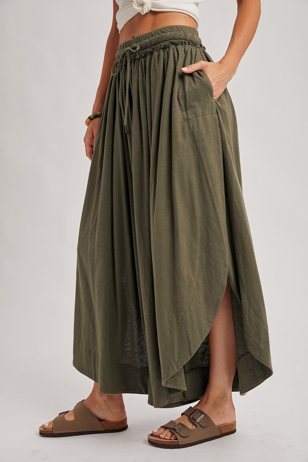 woman wearing an olive green maxi skirt with a high slit and side pockets