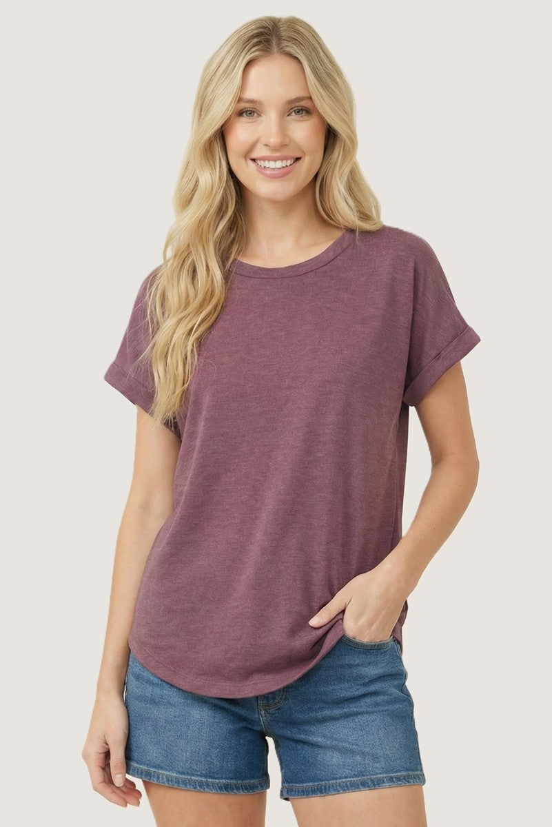 woman wearing a maroon short sleeve t-shirt with rolled cuffs and blue denim shorts, smiling at the camera