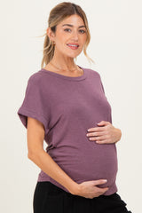 woman wearing a purple short sleeve maternity top and holding her baby bump