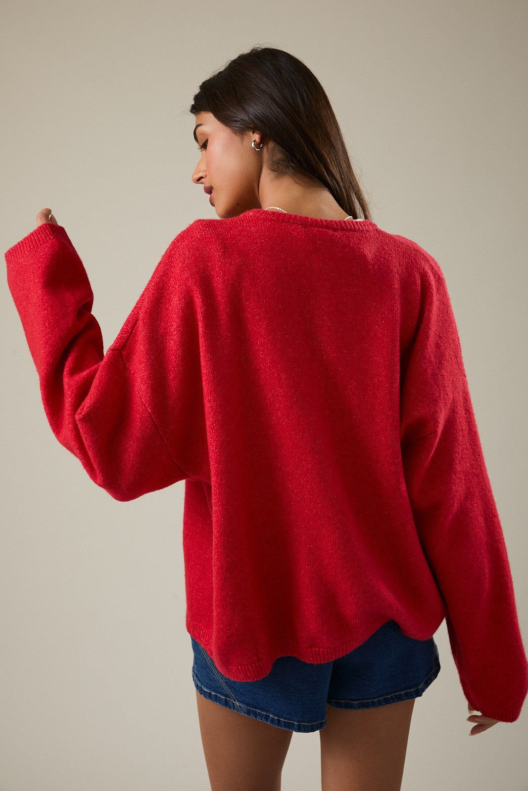 woman wearing a red oversized sweater with long sleeves and a relaxed fit, shown from the back