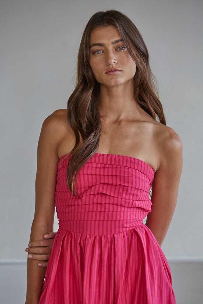 woman wearing a bright pink strapless dress with a pleated bodice and flowing skirt