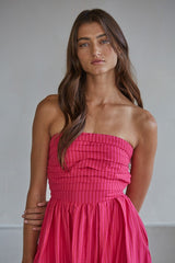 woman wearing a bright pink strapless dress with a pleated bodice and flowing skirt