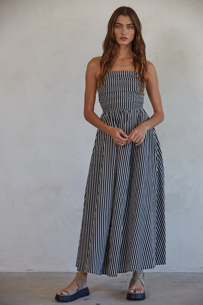 woman wearing a black and white striped maxi dress with a smocked bodice and aFlowy skirt