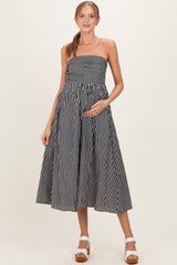 woman wearing a black and white striped strapless maternity dress with a fitted bodice and flowing skirt, showing her baby bump