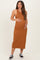 woman wearing a rust-colored sleeveless maternity maxi dress and holding her baby bump