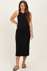 woman wearing a black fitted maternity midi dress and standing with a visible baby bump
