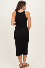 woman wearing a black maternity midi dress with a fitted silhouette, showing a side view and no baby bump visible