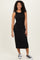 woman wearing a fitted black tank dress with a midi length and sneakers, standing confidently with a smile