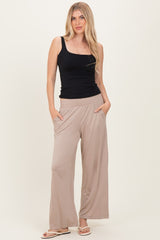 woman wearing a black sleeveless top and beige wide-legged pants with pockets