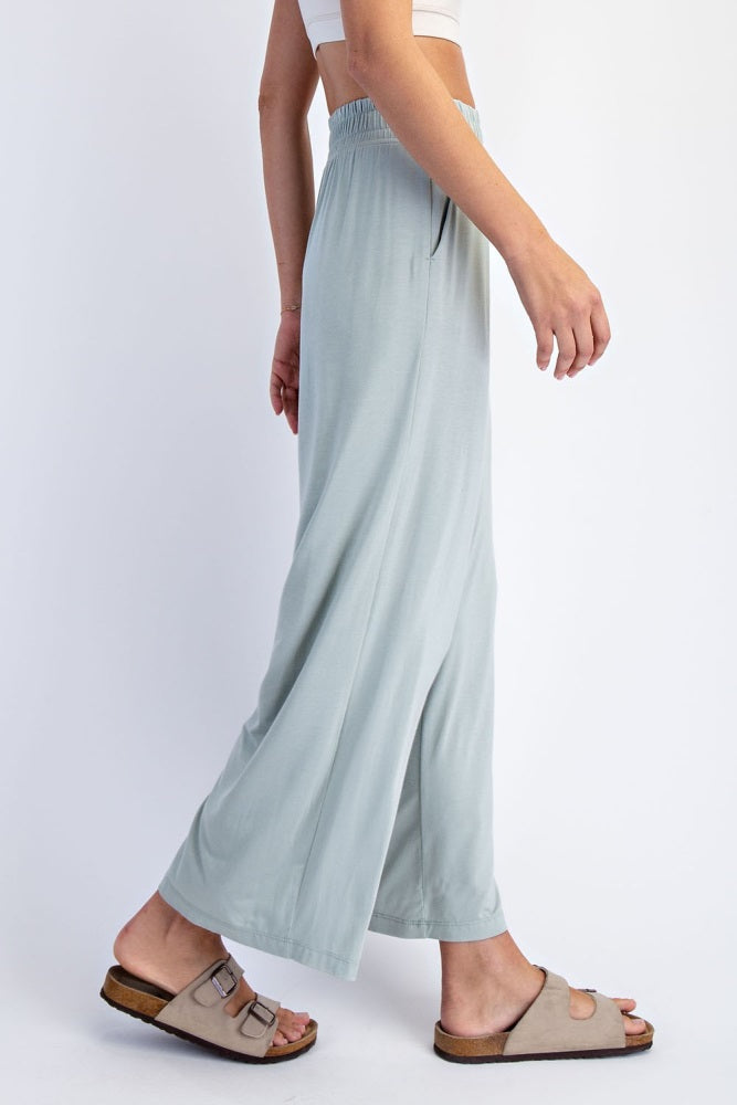 woman wearing light green wide leg pants with an elastic waistband and casual slide sandals