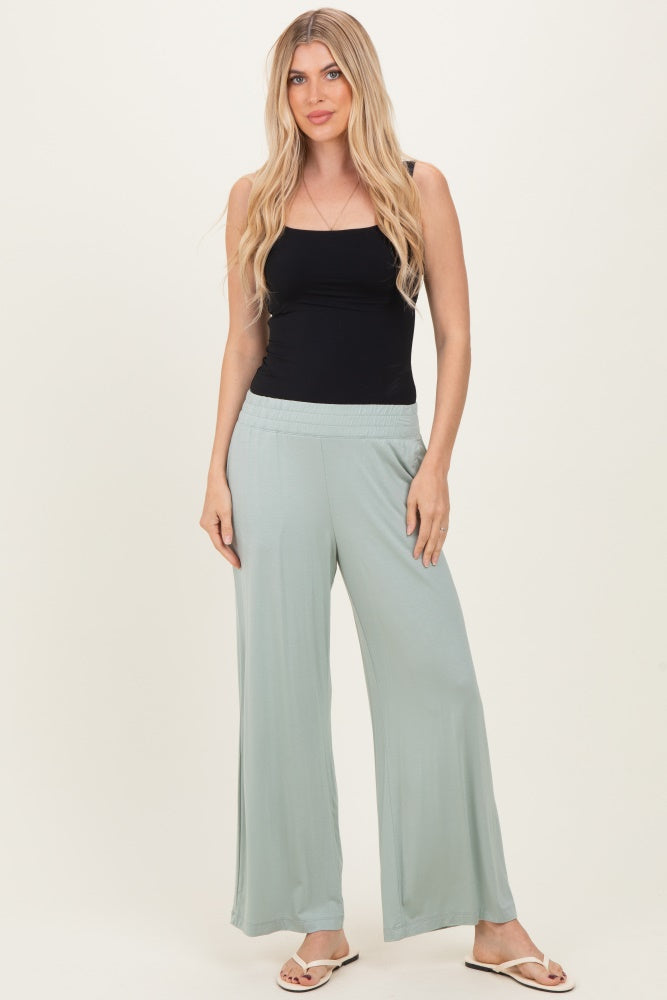 woman wearing a black tank top and light green wide-leg pants with a smocked waistband